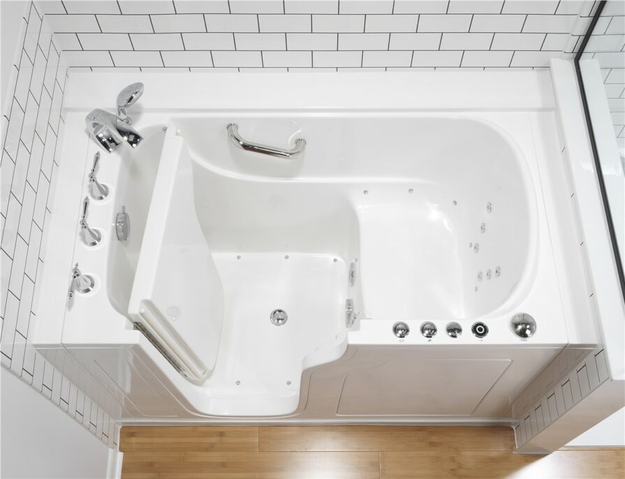 Overhead view of a white walk-in tub with safety grab bar, built-in seat, and chrome fixtures in a bathroom with subway tile walls and wood flooring.